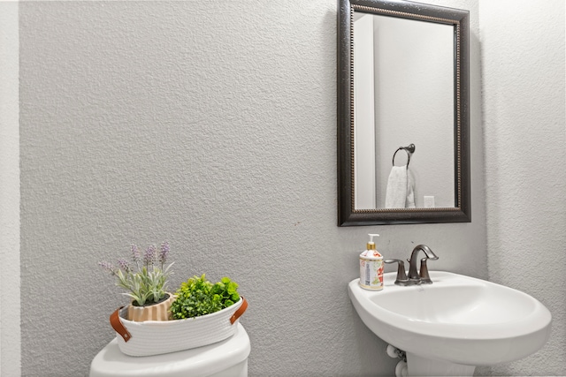 bathroom featuring a textured wall and a sink