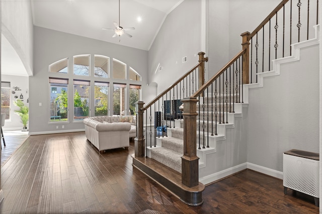 staircase with high vaulted ceiling, baseboards, and hardwood / wood-style flooring