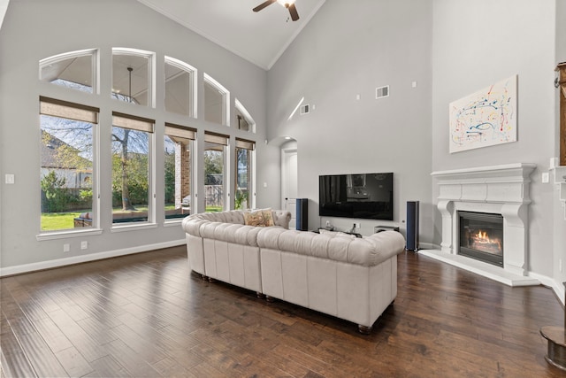 living room featuring dark wood-style floors, baseboards, visible vents, and a glass covered fireplace