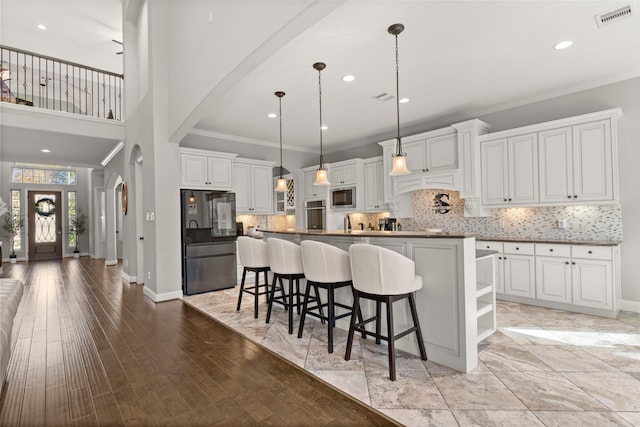 kitchen with arched walkways, stainless steel appliances, visible vents, ornamental molding, and baseboards