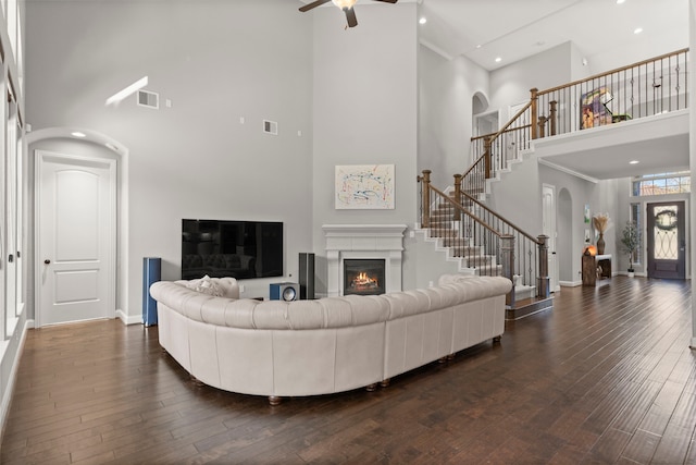 living room featuring visible vents, dark wood finished floors, baseboards, and stairs