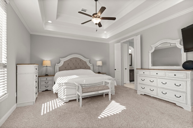 bedroom with visible vents, a raised ceiling, light colored carpet, ensuite bathroom, and crown molding