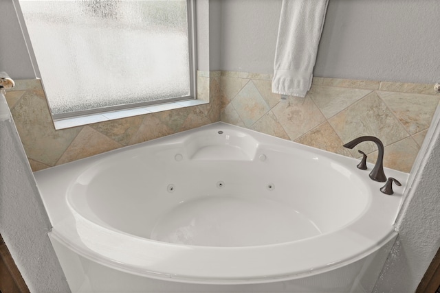 full bathroom with a textured wall and a jetted tub