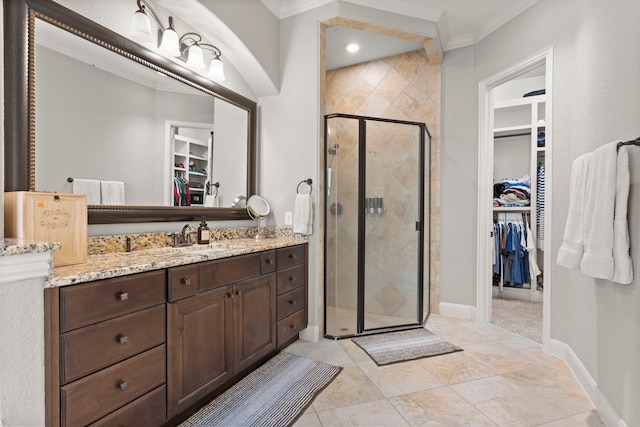 bathroom featuring crown molding, a spacious closet, a stall shower, vanity, and baseboards