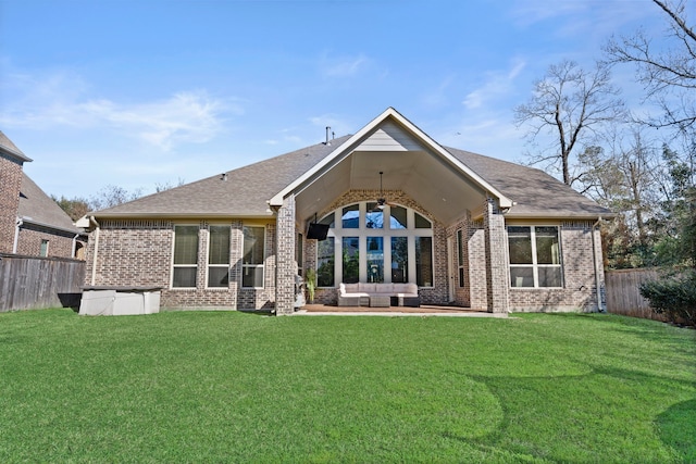 rear view of house featuring a fenced backyard, a yard, a patio area, an outdoor living space, and brick siding