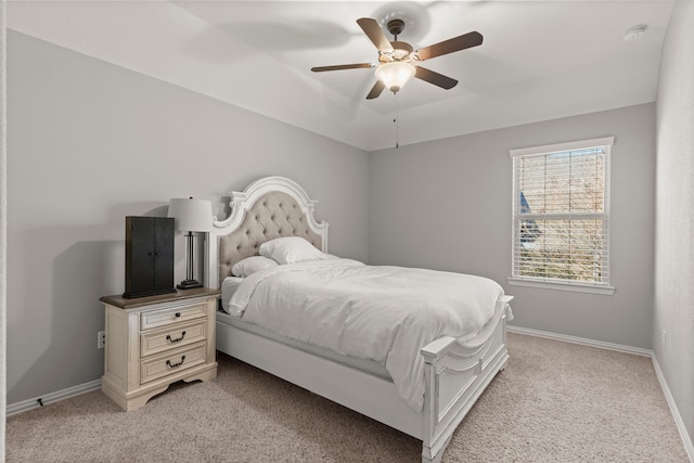 bedroom with a ceiling fan, a tray ceiling, light carpet, and baseboards