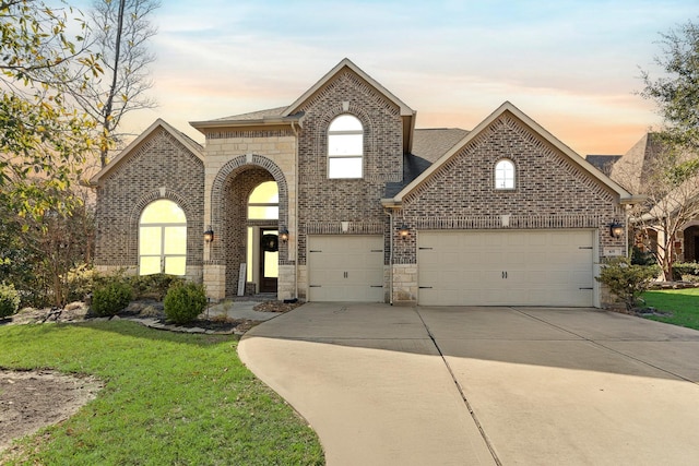 view of front of home featuring brick siding, driveway, and a lawn