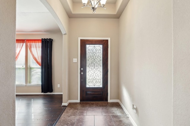 foyer with baseboards, arched walkways, and a notable chandelier