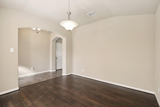 empty room featuring lofted ceiling, arched walkways, dark wood-style flooring, visible vents, and baseboards