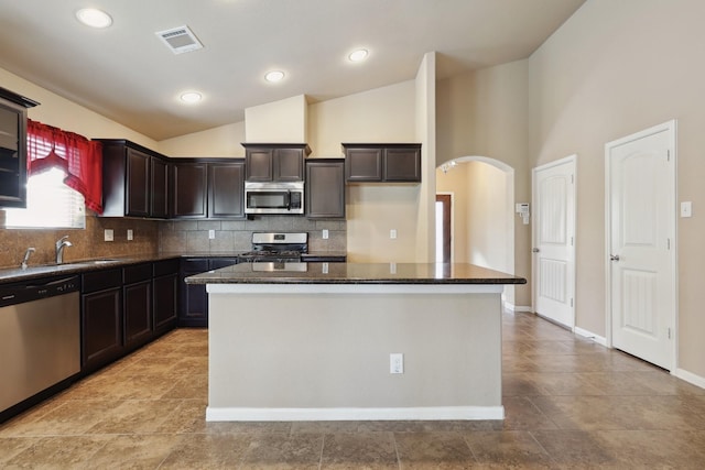 kitchen with visible vents, arched walkways, appliances with stainless steel finishes, vaulted ceiling, and a sink