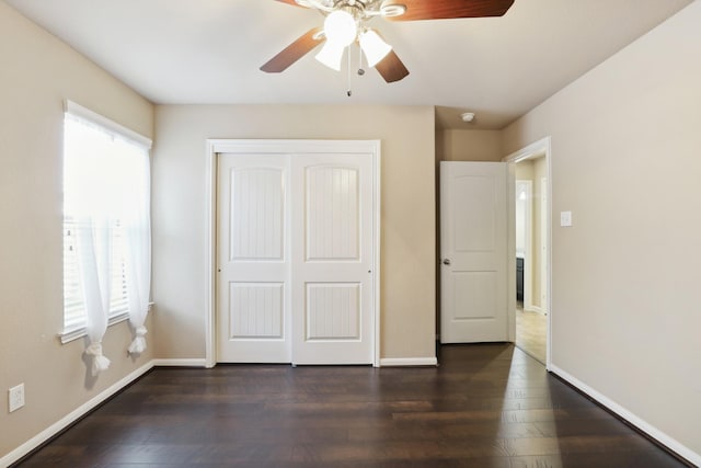 unfurnished bedroom featuring dark wood-style floors, a closet, a ceiling fan, and baseboards