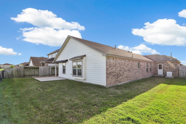 back of property with a yard, a patio, brick siding, and a fenced backyard