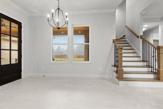 entryway with a chandelier, wood finished floors, baseboards, stairs, and ornamental molding