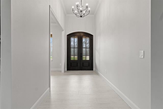 entrance foyer with arched walkways, a chandelier, baseboards, french doors, and ornamental molding