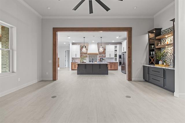 living area featuring ornamental molding, light wood-style floors, baseboards, and a ceiling fan