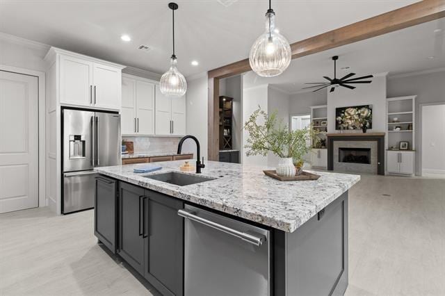 kitchen with a fireplace, appliances with stainless steel finishes, ornamental molding, white cabinets, and a sink