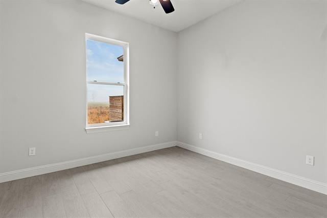 unfurnished room featuring ceiling fan, light wood finished floors, and baseboards