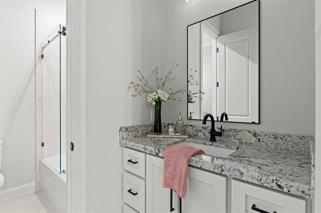 full bathroom with baseboards, vanity, and toilet