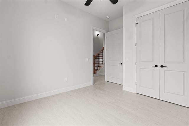 unfurnished bedroom featuring a ceiling fan, light wood-type flooring, a closet, and baseboards