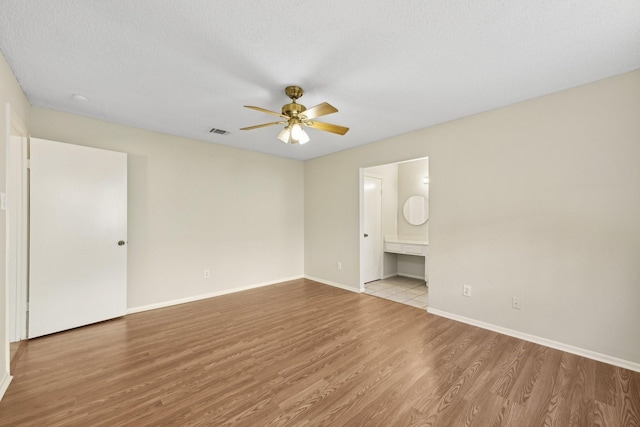 interior space with ceiling fan, visible vents, baseboards, and wood finished floors