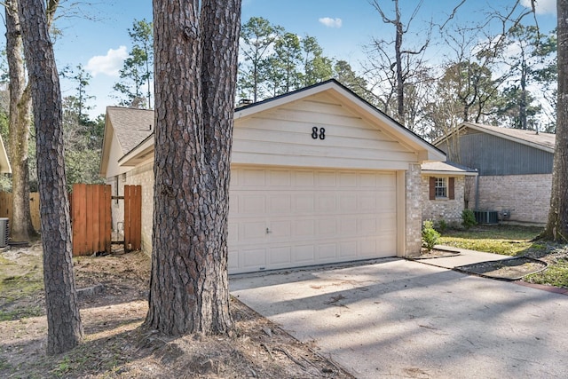 garage with central AC, fence, and concrete driveway