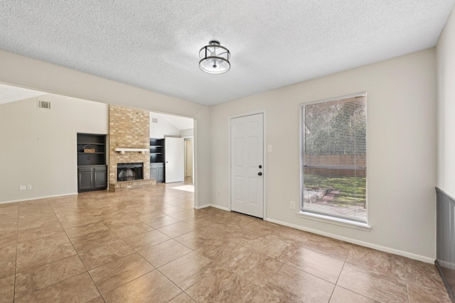 unfurnished living room featuring a brick fireplace, tile patterned flooring, visible vents, and a textured ceiling