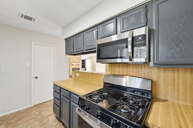 kitchen with a textured ceiling, light tile patterned floors, visible vents, light countertops, and appliances with stainless steel finishes