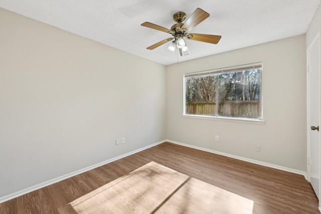 empty room with a ceiling fan, a textured ceiling, baseboards, and wood finished floors