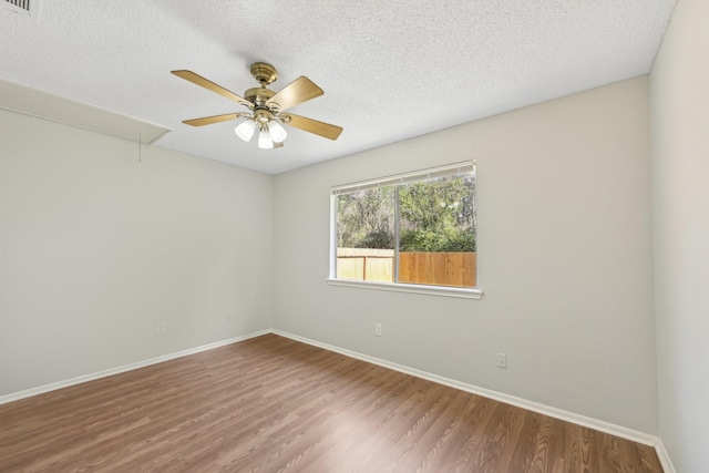 empty room with a textured ceiling, wood finished floors, and attic access