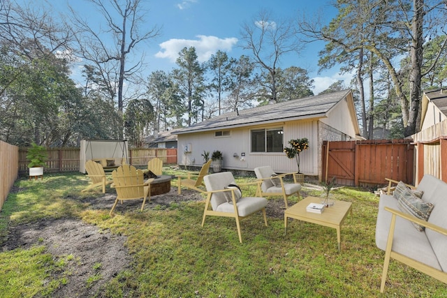 rear view of property featuring an outdoor fire pit, a gate, a fenced backyard, and a yard