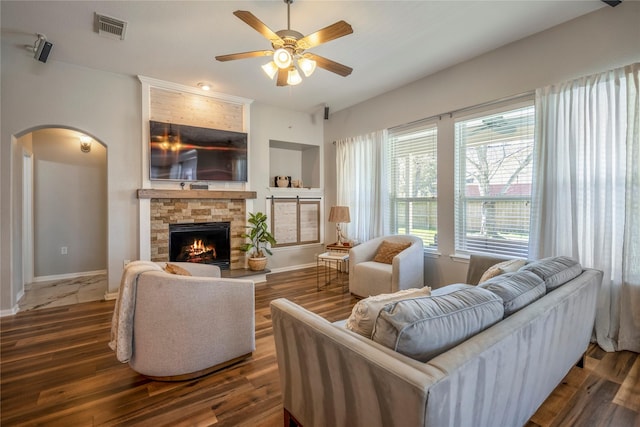 living area featuring arched walkways, visible vents, a fireplace, and wood finished floors