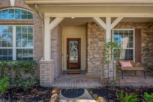 doorway to property featuring brick siding and covered porch