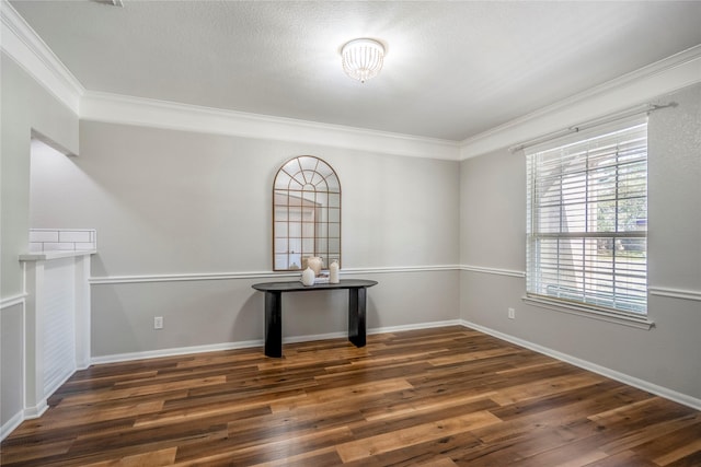 spare room featuring crown molding, baseboards, and wood finished floors