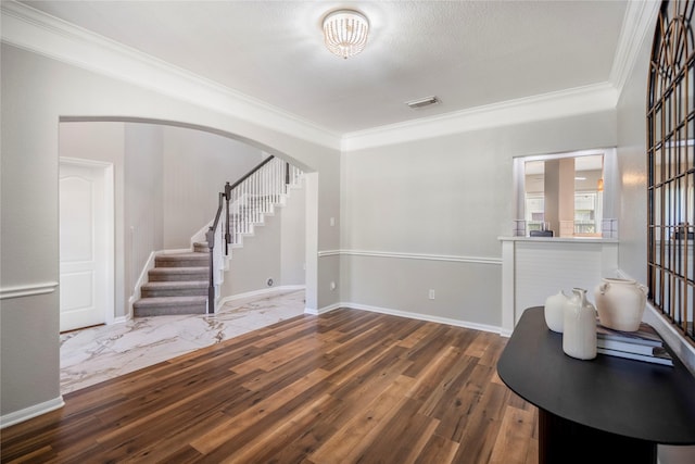 unfurnished room featuring wood finished floors, visible vents, baseboards, stairs, and crown molding