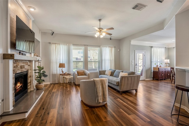 living area with visible vents, a fireplace, baseboards, ceiling fan, and dark wood-style flooring