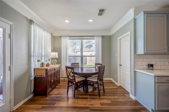 dining room with dark wood-type flooring, baseboards, visible vents, and ornamental molding