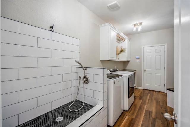 washroom featuring dark wood finished floors, visible vents, and independent washer and dryer