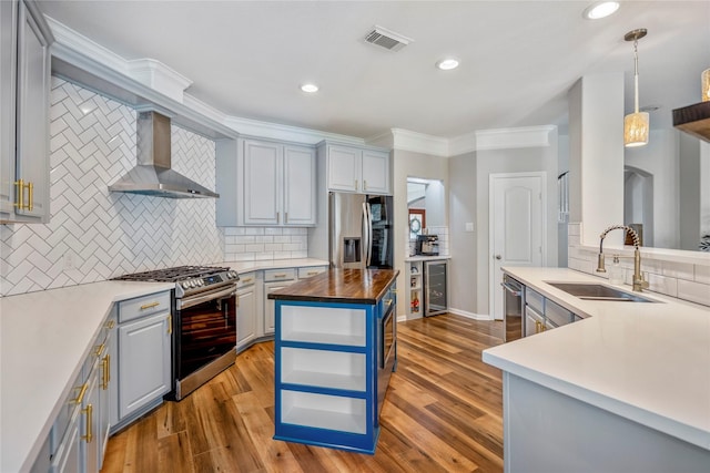 kitchen featuring visible vents, gray cabinets, a sink, stainless steel appliances, and wall chimney exhaust hood