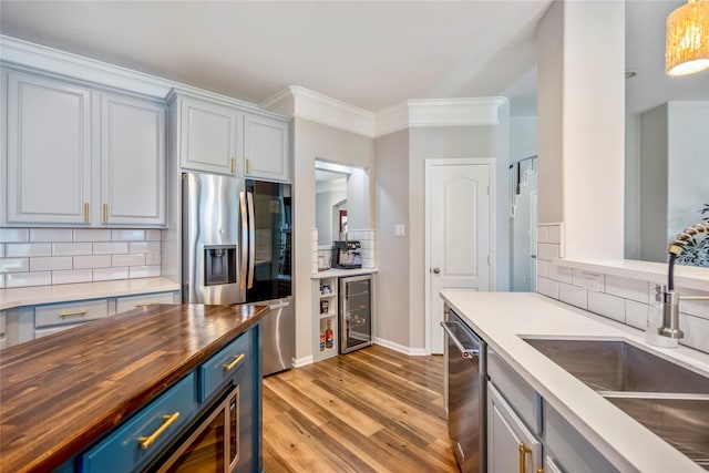 kitchen with appliances with stainless steel finishes, blue cabinetry, wooden counters, and a sink