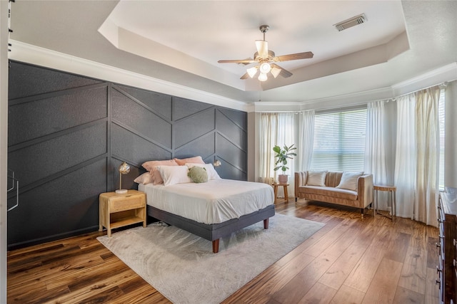 bedroom with visible vents, a raised ceiling, and hardwood / wood-style floors