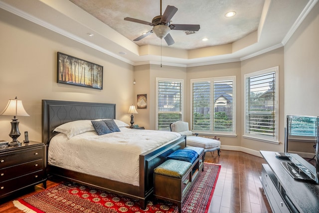 bedroom featuring dark wood-type flooring, a tray ceiling, visible vents, and baseboards