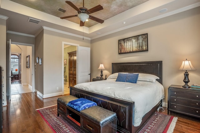 bedroom featuring wood finished floors, a raised ceiling, visible vents, and baseboards