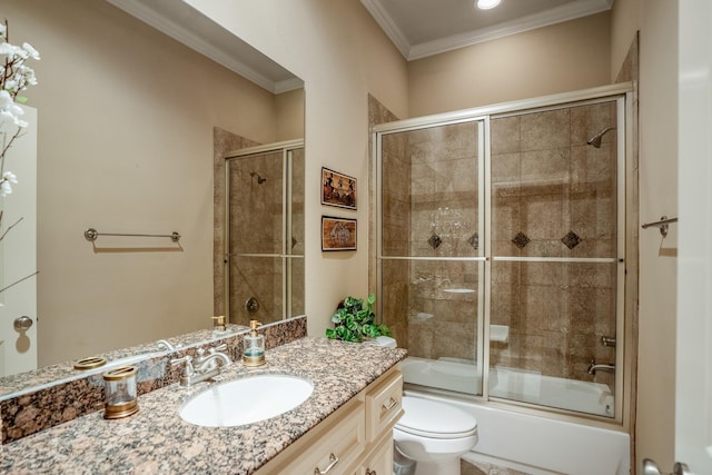 bathroom featuring toilet, combined bath / shower with glass door, crown molding, and vanity