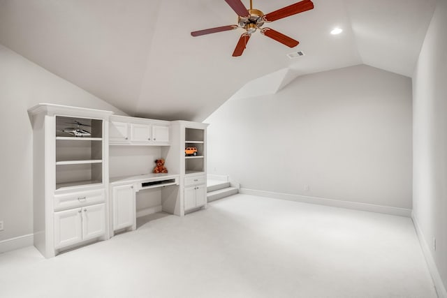 unfurnished living room with baseboards, visible vents, light colored carpet, built in study area, and vaulted ceiling