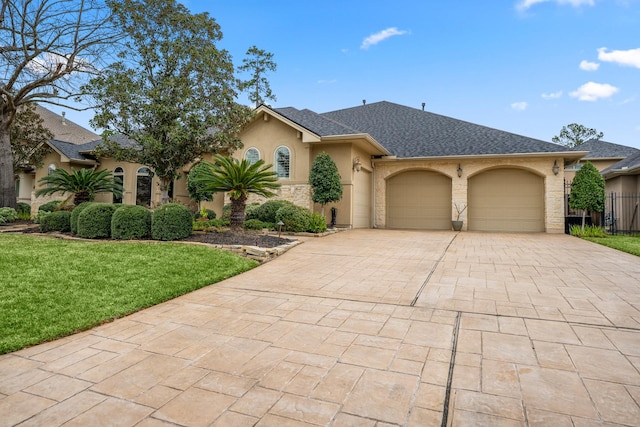 view of front of house featuring a garage, roof with shingles, decorative driveway, stucco siding, and a front yard