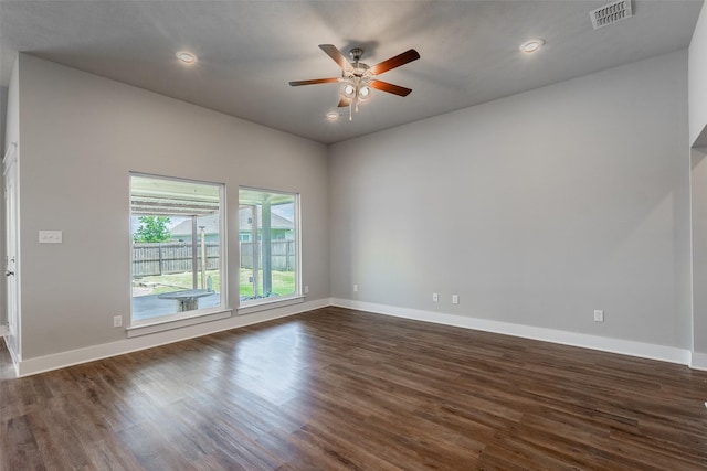 spare room with dark wood-style flooring, visible vents, and baseboards