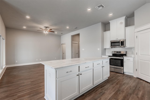 kitchen featuring appliances with stainless steel finishes, a center island, visible vents, and dark wood-type flooring