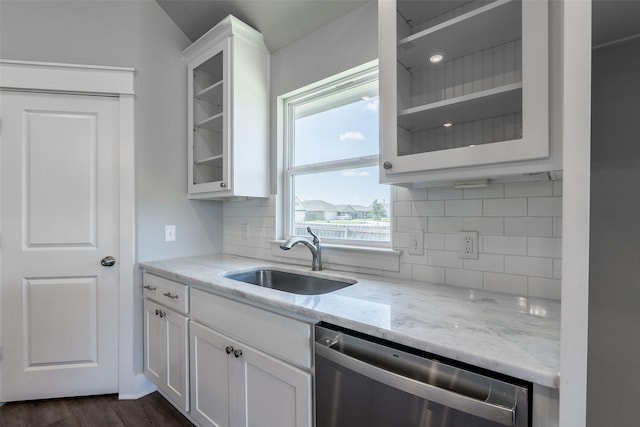 kitchen featuring stainless steel dishwasher, a sink, light stone counters, and white cabinets