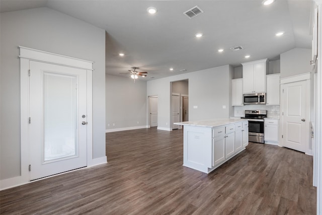 kitchen featuring visible vents, dark wood-type flooring, a center island, stainless steel appliances, and white cabinetry