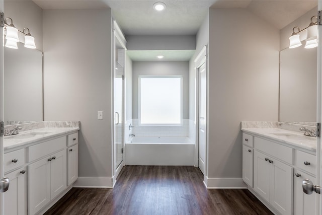 full bath featuring a shower stall, baseboards, a sink, and wood finished floors